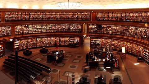 Blick von der Empore auf Bücherregale an der Wand einer großen Bibliothek.