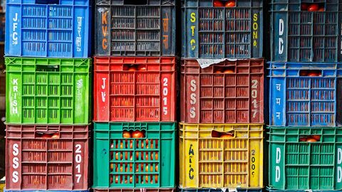 Aufeinandergestapelte bunte Plastikkisten mit Lebensmitteln gefüllt.