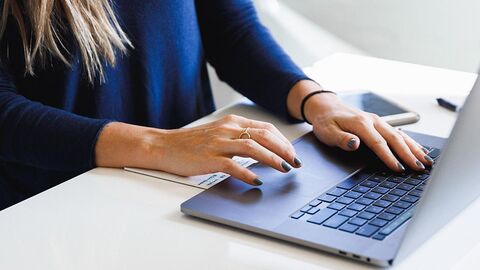 Frau tippt auf einem Laptop; Bildausschnitt.