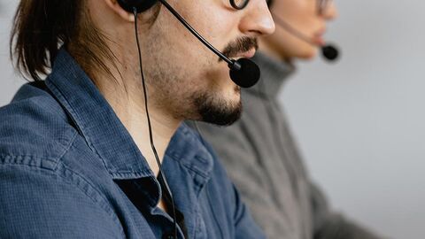 Zwei Personen nebeneinander, beide mit Headset.